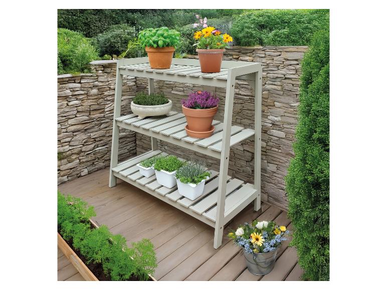 Houten drielaags plantenrek gevuld met diverse planten en bloemen op een terras.