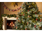Besneeuwde kerstboom met decoraties en brandende open haard, slinger en adventskalender.