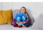 Lachend meisje knuffelt blauw pluche dier op grijze bank met kussens.