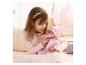 Meisje in roze top speelt met babypop in roze outfit en speen.