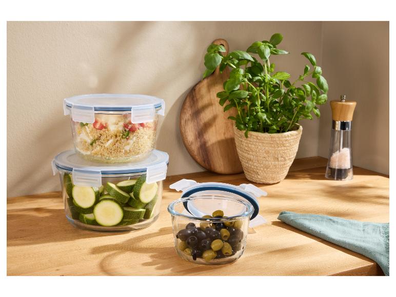 Glazen voedselbewaarbakjes met verse ingrediënten op een houten aanrecht.