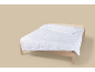 Wit dekbed met een golvend patroon op een houten bed.
