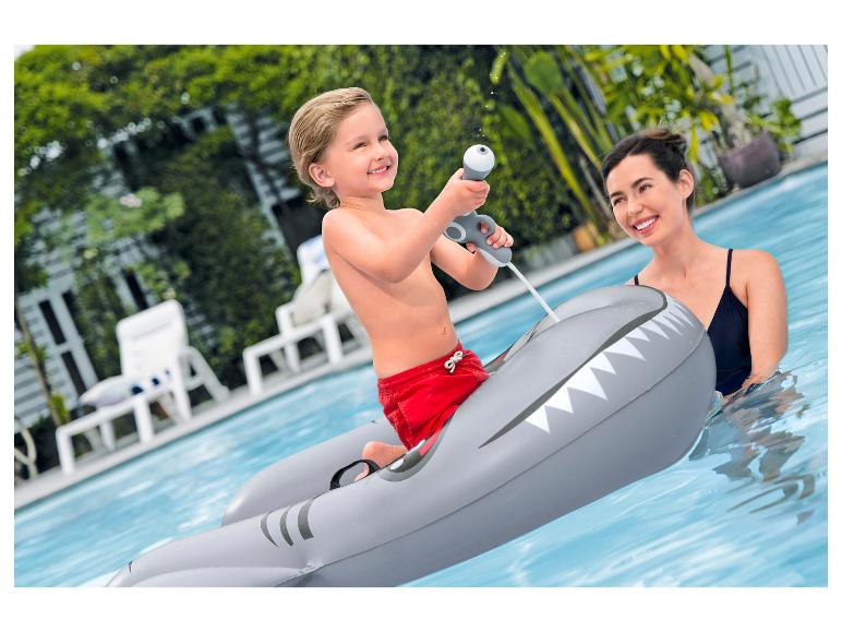Jongen op haai-zwemband met waterpistool in zwembad met vrouw.