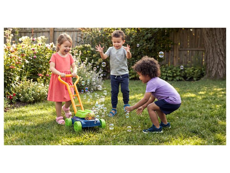 Drie blije kinderen spelen met een bellenblaas grasmaaier in een zonnige tuin.