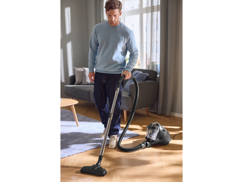 Man stofzuigt een houten vloer in een woonkamer.
