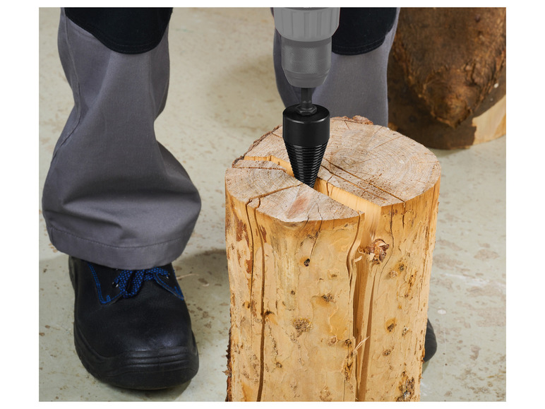 Een persoon gebruikt een boormachine om een houtklover in een boomstam te bevestigen.