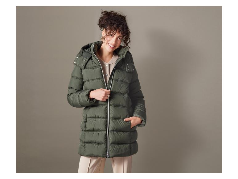 Een vrouw in een groene gewatteerde jas met capuchon.