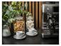 Espressomachine, twee koffiekopjes, koekjes en meringues in glazen potten.