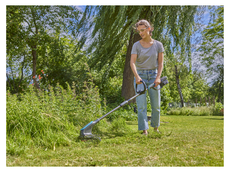Een vrouw gebruikt een Gardena elektrische bosmaaier in haar tuin.