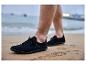 Zwarte herenschoenen op het zand, met de zee op de achtergrond.