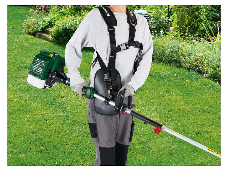 Persoon gebruikt een bosmaaier met harnas in een groene tuin.