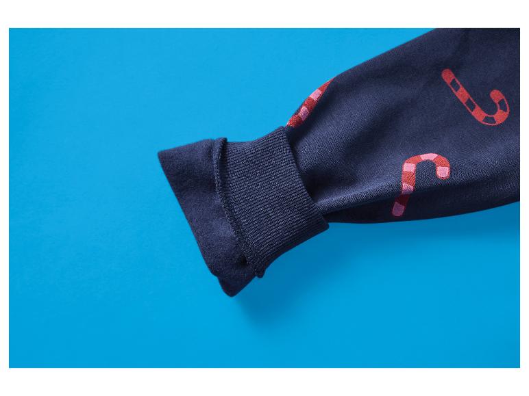 Donkerblauwe mouw van een sweatshirt met rode en roze zuurstokpatronen op een blauwe achtergrond