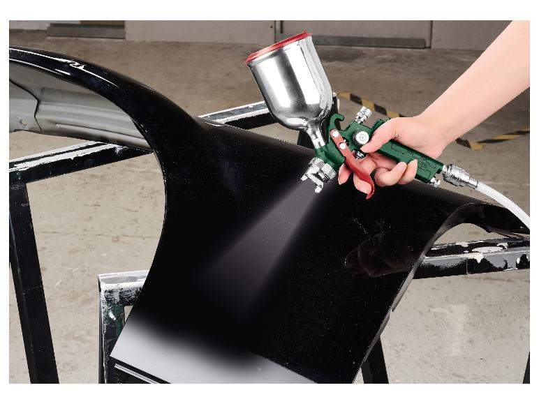 Hand spuit verf op een zwart auto-onderdeel met een spuitpistool