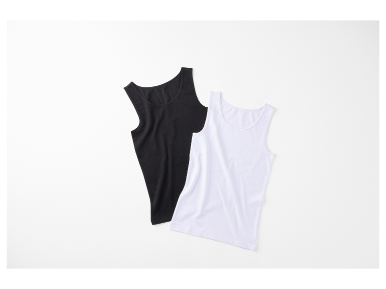 Twee effen tanktops, een zwarte en een witte, liggen op een witte achtergrond.