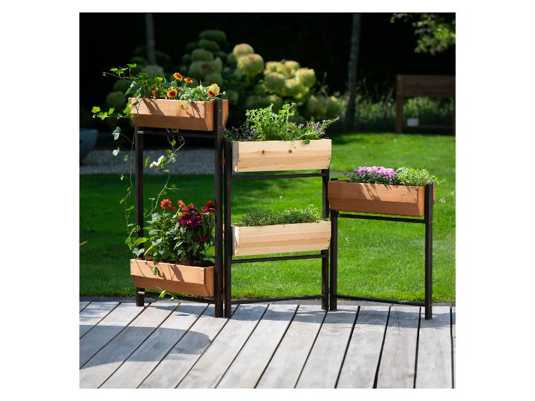 Gelaagde houten plantenbak met diverse bloemen en kruiden op een terras.