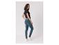 Vrouw in zwart t-shirt en blauwe skinny jeans, over haar schouder kijkend.