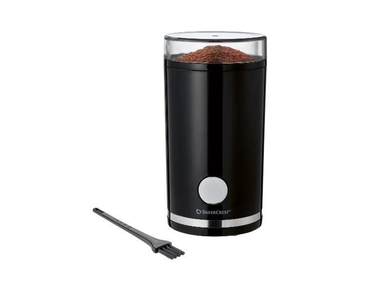 Zwarte elektrische koffiemolen met gemalen koffie en schoonmaakborstel.