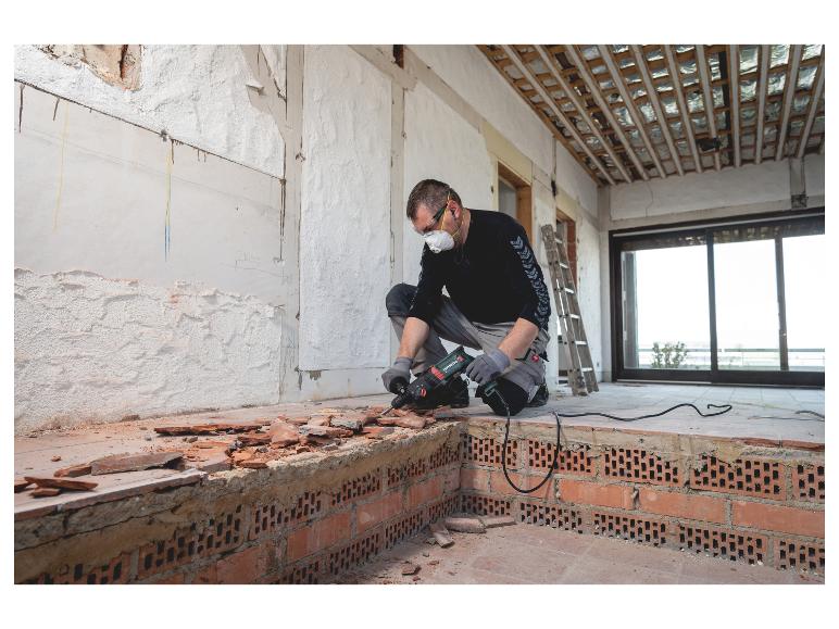 Man verwijdert vloertegels met een Metabo boorhamer tijdens renovatie