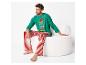 Man zit op witte stoel in groene kerstpyjama met 'let's take an Elfie' tekst en rood-wit gestreepte broek.