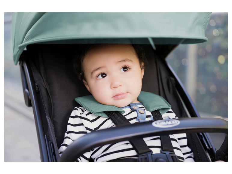 Baby in een kinderwagen, met gestreept shirt en groene kraag.