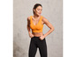 Vrouw in een oranje sportbeha en zwarte leggings.