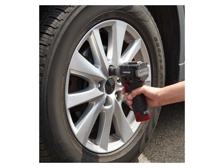 Een man gebruikt een draadloze Parkside schroevendraaier om een wiel te bevestigen.