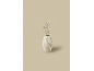 Een witte keramische vaas met kleine witte bloemetjes op een beige achtergrond.