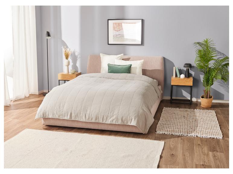 Bed met beige dekbed en tapijten: minimalistische slaapkamer.