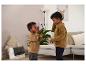 Twee jongens in bruine sweatshirts spelen met een walkie-talkie in een woonkamer.