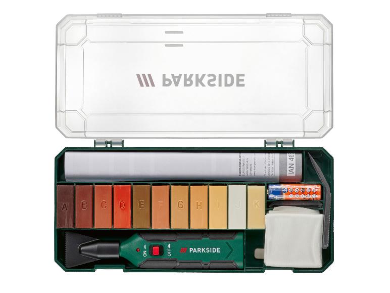 Een vloerreparatieset met 11 gekleurde wasstiften, een applicator en accessoires, in een groene doos.