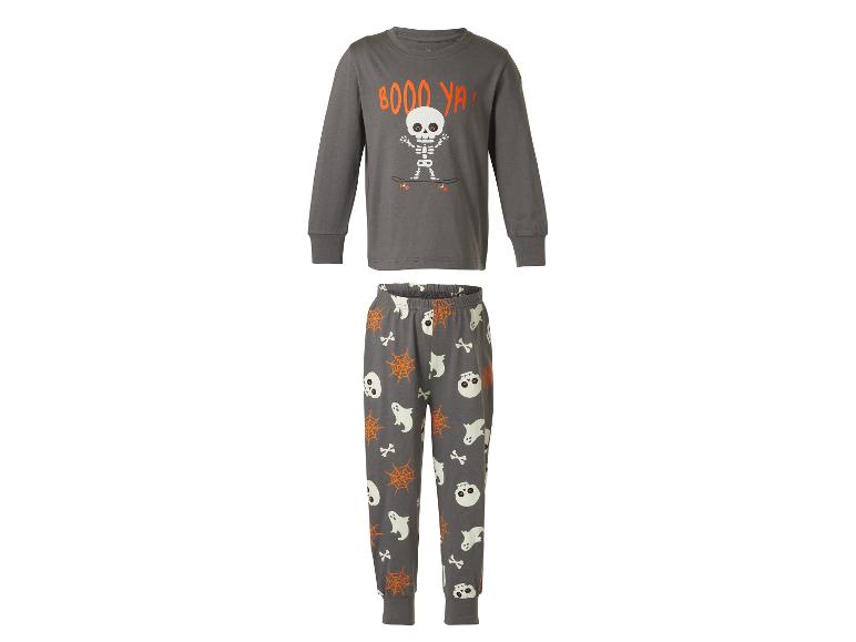 Kinder Halloween pyjama: grijs shirt met lange mouwen met een skelet op een skateboard en de tekst 'BOOO YA!', en bijpassende broek met spoken, schedels, spinnenwebben en botten.