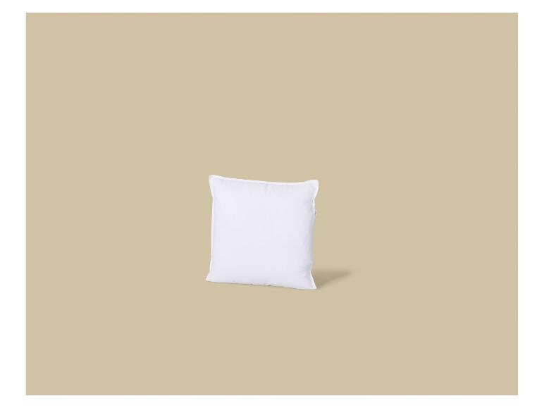 Een wit kussen met een kleine schaduw op een beige achtergrond.