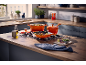 Oranje gietijzeren kookgerei op een gaskookplaat in een moderne keuken.