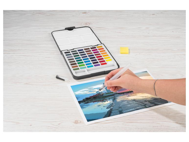 Een persoon schildert een kustscène met aquarelverf en een waterkwast.