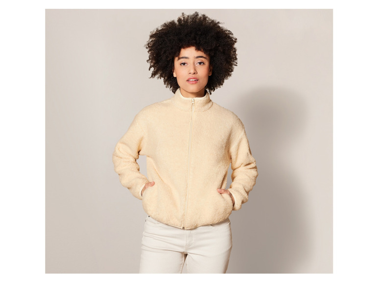 Een vrouw draagt een crèmekleurige fleecejas.