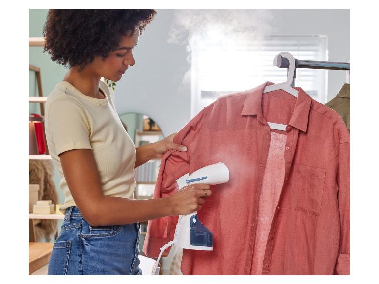 Een vrouw stoomt een overhemd met een stoomstrijkijzer.