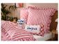 Slaapkamer met gestreepte rood-witte beddengoed en kussens met de teksten 'BLAH BLAH' en 'Bonjour'.