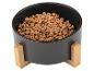 Een zwarte hondenvoerbak met houten standaard gevuld met hondenvoer.