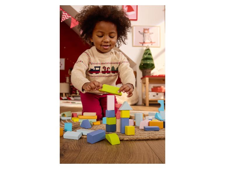 Een kind speelt met kleurrijke bouwblokken op een houten vloer.