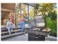 Gasbarbecue met eten en vier vrienden die genieten van een buitenbarbecue.