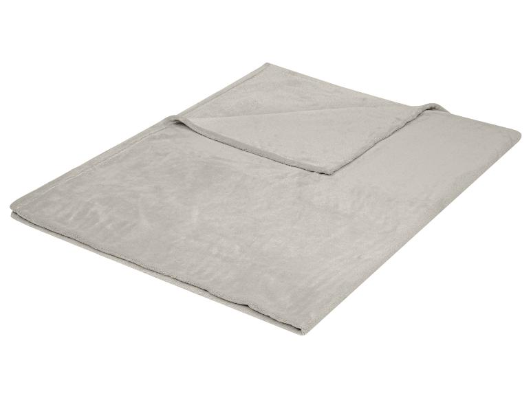 Grijze, zachte fleece deken opgevouwen op een witte achtergrond.