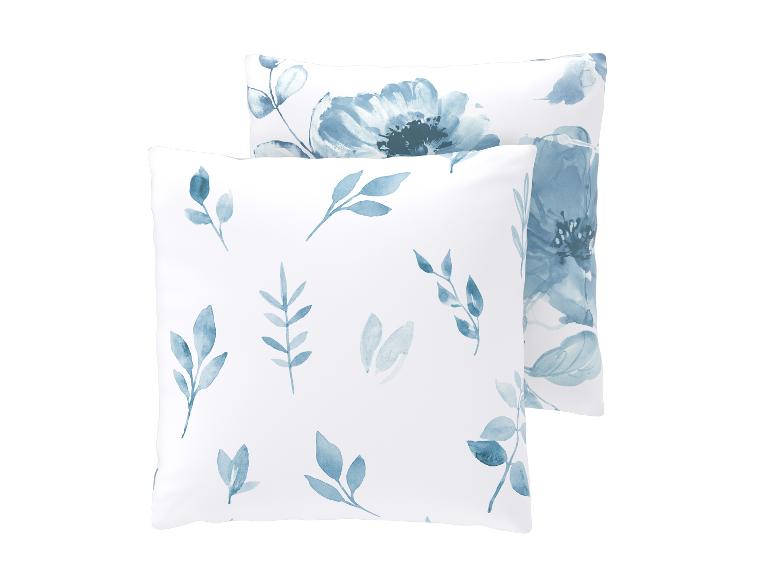 Twee witte kussens met blauwe aquarel bloemen- en bladprint.
