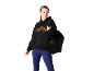 Vrouw in zwarte hoodie met oranje logo, blauwe legging en zwarte sporttas.