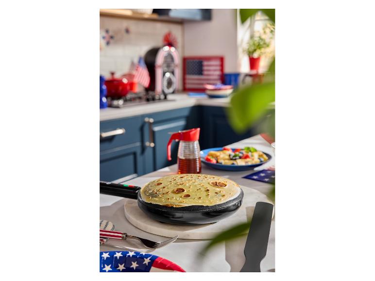 Elektrische crêpemaker met crêpe, siroop en bessenschotel, in een keuken met Amerikaans thema.