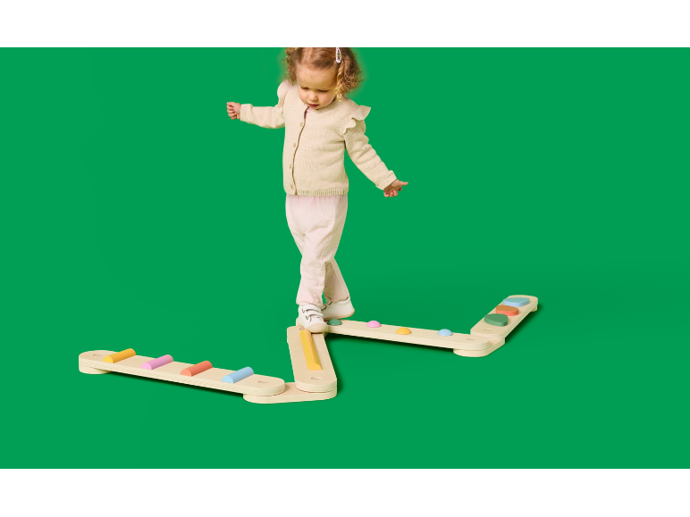 Peuter balanceert op een houten evenwichtsbalk met kleurrijke treden.