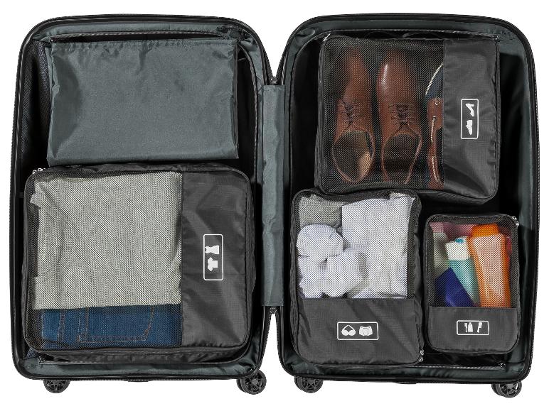 Georganiseerde koffer met inpakzakken voor kleding, schoenen en toiletartikelen.