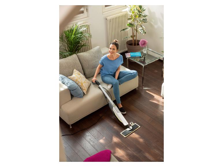 Vrouw op een bank reinigt een houten vloer met een vloerreiniger.