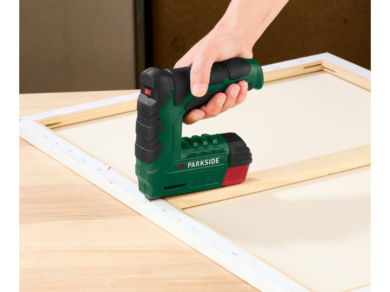 Hand gebruikt een Parkside elektrische tacker om canvas op een houten frame te spannen.