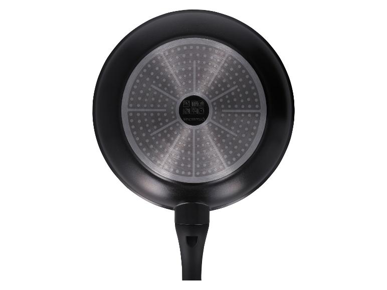 Onderkant van een zwarte koekenpan met een zilveren inductiebodem en een zwart handvat.