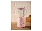 Roze blender met glazen kan op een houten tafel met lichte tegels op de achtergrond.